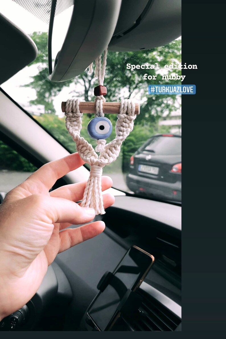 May include: A white macrame car charm with a blue evil eye bead and a wooden dowel. The charm is hanging from the rearview mirror of a car. The text "Special edition for hubby #TURKUA7LOVE" is visible in the image.