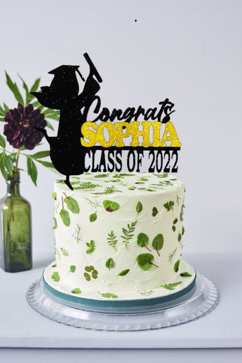 May include: Black and gold glitter graduation cake topper with the text "Congrats Sophia Class of 2022".