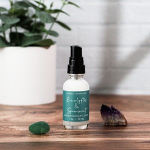 May include: A clear glass bottle with a black spray top. The bottle is labeled "A Girl's Gotta Spa! Eucalyptus & Spearmint Aromatherapy Spray 1 oz. | 30 ml."