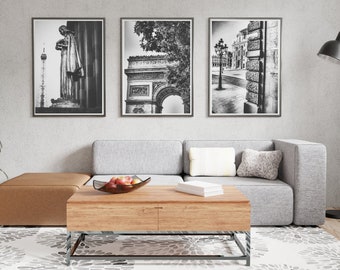 May include: A gray sectional sofa with a wooden coffee table and three black and white framed photographs of Parisian architecture. The coffee table has a glass bowl with fruit on it.