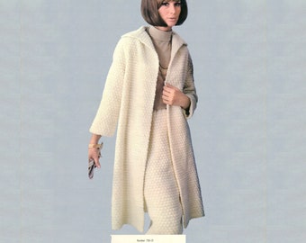 May include: A woman wearing a cream-colored, textured coat and skirt ensemble. The long coat has a hood and is open in the front, revealing a matching skirt and a light brown turtleneck. The outfit is accessorized with a gold bracelet and necklace.