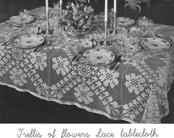 May include: A white crocheted tablecloth with a trellis pattern and floral designs. The tablecloth is set for a formal dinner with plates, silverware, and glasses.