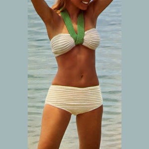 Puede incluir: Un bikini de crochet blanco con tirantes verdes. La parte superior es de estilo bandeau y la parte inferior es de cintura alta.