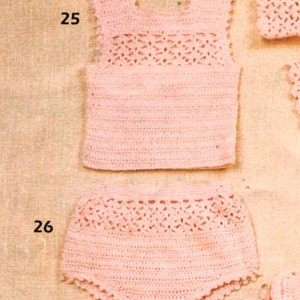 May include: A pink crocheted baby outfit with a sleeveless top and shorts. The top has a delicate lace pattern and the shorts have a ruffled hem.