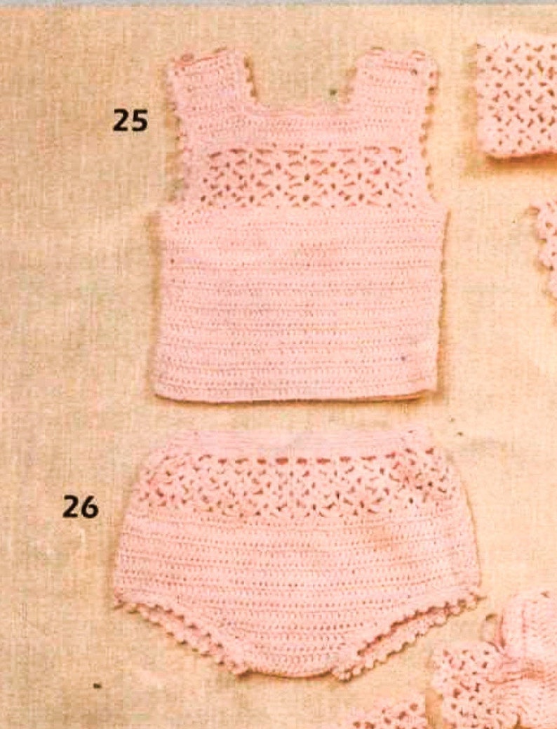 May include: A pink crocheted baby outfit with a sleeveless top and shorts. The top has a delicate lace pattern and the shorts have a ruffled hem.