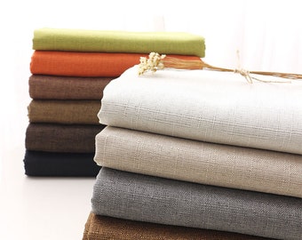 May include: A stack of fabric swatches in various colors, including green, orange, brown, beige, gray, and dark brown. The fabric has a linen texture.