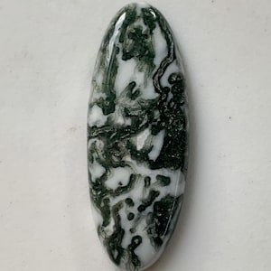 Op de afbeelding: Een ovale edelsteen met een gepolijst oppervlak. De steen heeft een witte basis met ingewikkelde donkergroene patronen, waardoor een marmer effect ontstaat. De edelsteen is ongeveer 3,8 cm lang.