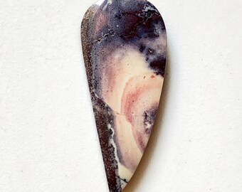 May include: A teardrop-shaped gemstone with a polished surface. The stone features a swirling pattern of colors, including deep purple, cream, and reddish-pink hues. The stone has a dark brown edge and a smooth, glossy finish.