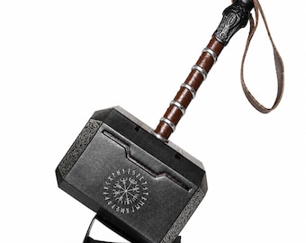 May include: A replica hammer featuring a dark metallic head with intricate silver-toned engravings and a circular runic symbol. The handle is brown with silver bands and a black pommel, finished with a brown leather wrist strap attached at the end.