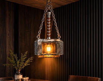 May include: A hanging pendant light fixture shaped like a hammer, featuring a metallic silver finish with intricate side engravings, a brown leather-wrapped handle, and a central Edison-style light bulb suspended by silver-toned metal chains.