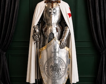 May include: A full suit of polished steel plate armor featuring a helmet with a gold cross, a white cape with a red cross, and a metal shield. The shield displays a central circular engraving of a mounted knight and a decorative border.