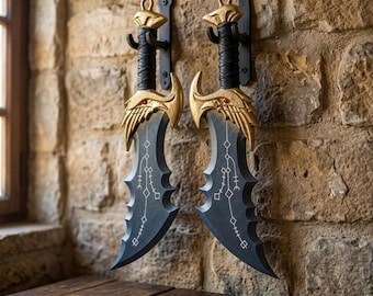 May include: Two curved blades with black, textured surfaces featuring white geometric line patterns. The hilts are wrapped in black material with gold-colored guards shaped like wings, each accented with a small red gem, mounted on black wall hooks.