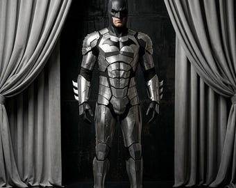 May include: A full-body suit of silver metallic armor featuring a dark bat-shaped emblem on the chest, segmented plating across the torso, arms, and legs, and a black cowl with pointed ears covering the head and face, worn with black gloves.