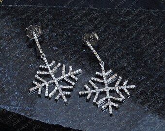 May include: A pair of silver snowflake earrings with clear cubic zirconia stones. The earrings are dangling and have a post back.