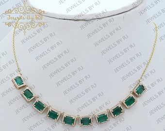 May include: A gold chain necklace with emerald green rectangular gemstones set in gold. The necklace is on a white background with the text "Jewels By RJ" repeated.
