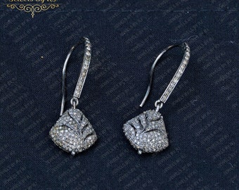 May include: A pair of silver dangle earrings with a diamond-shaped design. The earrings have a delicate, intricate design with small diamonds set in a silver frame. The earrings are a classic and elegant style that would be perfect for any occasion.