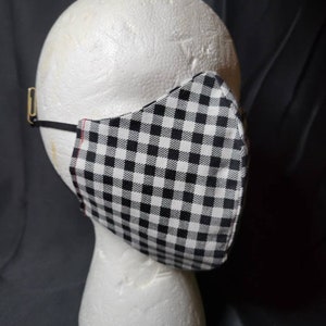 May include: A black and white gingham face mask on a white mannequin head. The mask has a red seam around the edges.