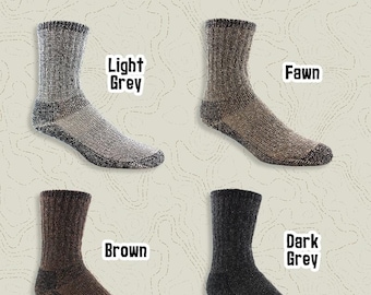 May include: Four pairs of alpaca wool socks in different colors: light grey, fawn, brown, and dark grey. The socks are midweight, full cushion, and crew length. The socks are labeled "The Survival Sock" and "Mother Nature's Finest Fiber USA Alpaca".