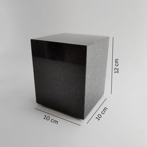 Peut inclure: Un cube en granit noir, mesurant 10 cm x 10 cm x 12 cm. La surface supérieure est polie, tandis que les côtés présentent une texture mouchetée. Forme géométrique solide, utilisable à des fins décoratives ou fonctionnelles.