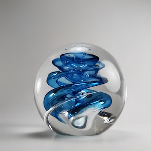 Peut inclure: Un presse-papier en verre transparent avec un motif en verre bleu en spirale à l'intérieur. Le verre bleu est en forme de spirale.