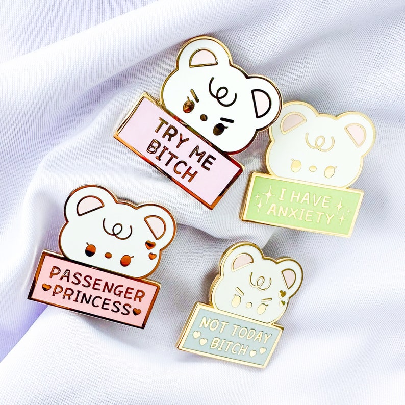 Op de afbeelding: Set van vier emaillepins met cartoonberen met verschillende spreuken. De pins bevinden zich op een witte achtergrond. De spreuken op de pins zijn "Try Me Bitch", "I Have Anxiety", "Passenger Princess" en "Not Today Bitch".