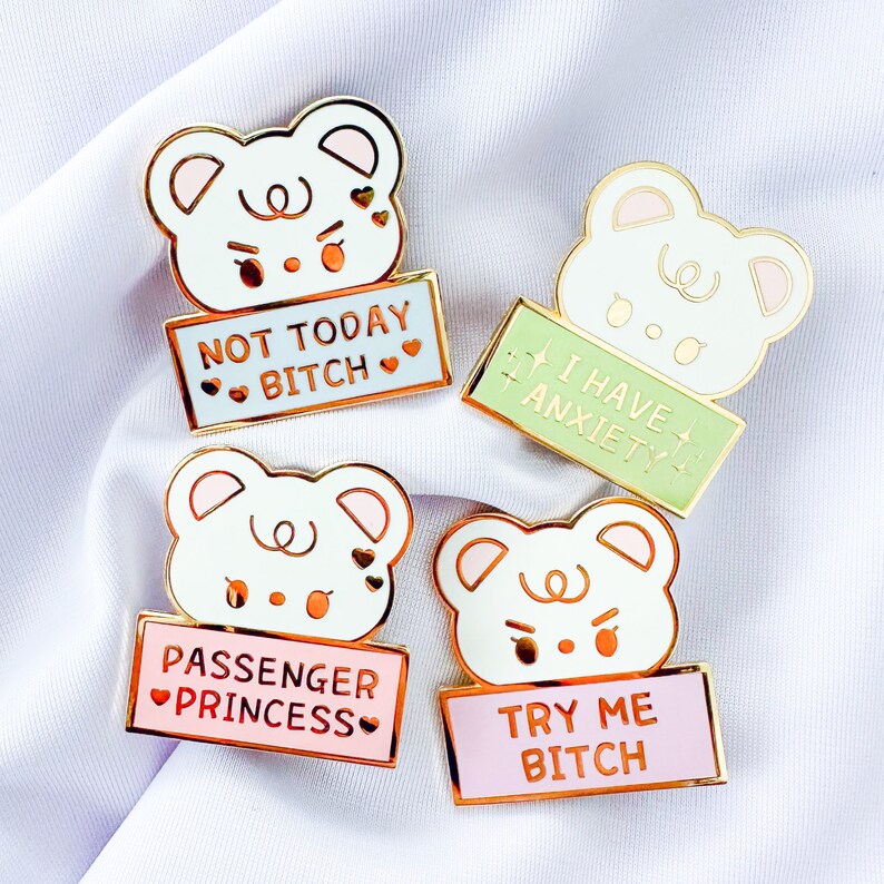 Op de afbeelding: Vier emaillepins met cartoonberen met verschillende spreuken. De eerste pin zegt "Not Today Bitch" in blauw met roze hartjes. De tweede pin zegt "I Have Anxiety" in groen met gouden sterren. De derde pin zegt "Passenger Princess" in roze met roze hartjes. De vierde pin zegt "Try Me Bitch" in roze met gouden sterren.