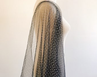 May include: Black sheer fabric with white polka dots draped over a white dress form.