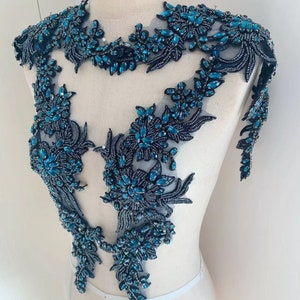 May include: A teal and black beaded applique with a floral design. The applique is made of beads and sequins and is perfect for adding a touch of sparkle to any garment.