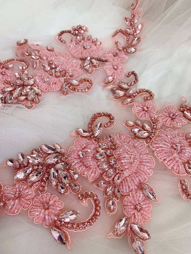 May include: Pink and rose gold beaded floral applique with rhinestones. This delicate embellishment features a floral design with intricate beading and sparkling rhinestones.