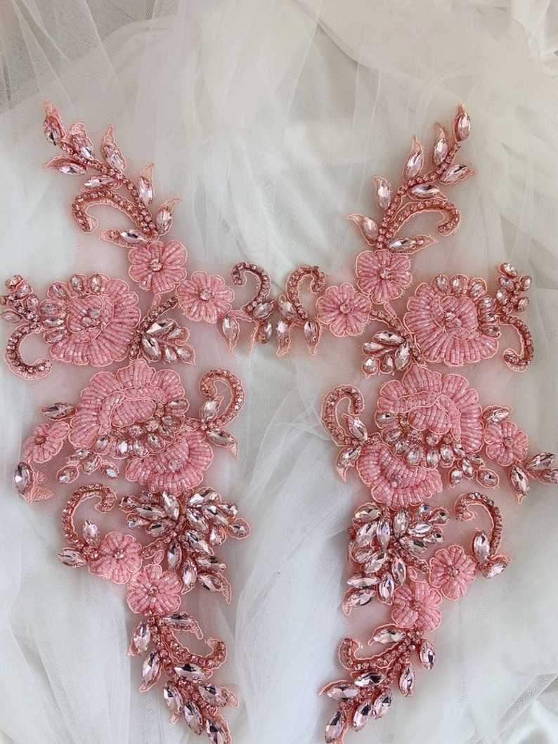 May include: Two pink beaded floral appliques with crystal embellishments. The appliques are perfect for adding a touch of elegance to any garment or craft project.