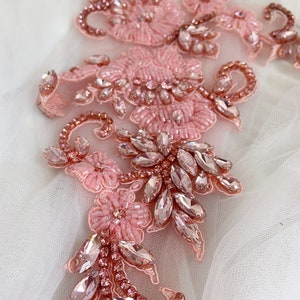 May include: Pink and rose gold beaded and rhinestone applique. The applique features a floral design with delicate beading and sparkling rhinestones.
