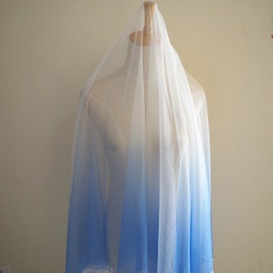 May include: A sheer white fabric with a blue ombre gradient. The fabric is draped over a dress form.