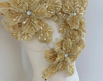 May include: Gold beaded and sequined floral applique with a rhinestone center. This embellishment is perfect for adding a touch of sparkle and elegance to any garment.