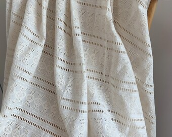 May include: White cotton fabric with a geometric pattern of circles and triangles. The fabric has a delicate, openwork design.