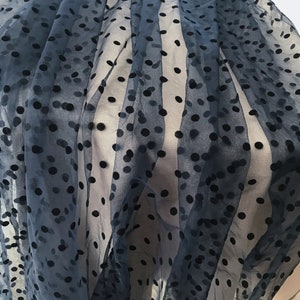 May include: Black sheer fabric with black polka dots. The fabric is soft and has a delicate texture.