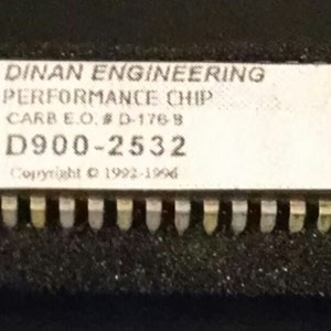 May include: A black circuit board with a white label that reads "DINAN ENGINEERING PERFORMANCE CHIP CARB E.O. #D-176-8 D900-2532 Copyright © 1992-1996".