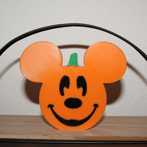 May include: Orange and black Halloween pumpkin shaped like Mickey Mouse with a green stem.