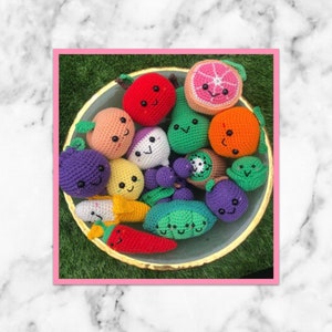 May include: A bowl filled with crocheted fruit and vegetable plushies. The plushies are all different colours and have cute faces. The bowl is on a green surface.