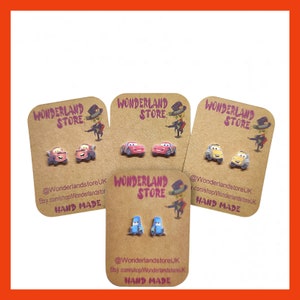 May include: Four pairs of handmade earrings featuring cartoon cars from the movie Cars. The earrings are on brown cards with the text "Wonderland Store" and "Hand Made".