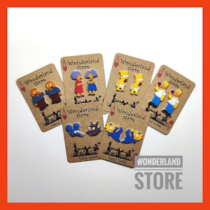 May include: Five pairs of handmade earrings featuring characters from the animated television show The Simpsons. Each pair is displayed on a brown card with the text "A Wonderland Store" and "hand made".