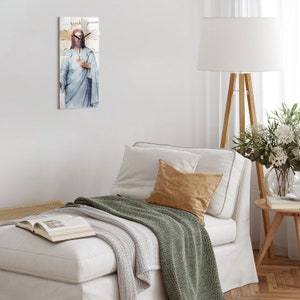 Puede incluir: Un sofá blanco con una manta de tiro verde y una almohada de color beige. Un reloj con una imagen de Jesús está colgado en la pared detrás del sofá.