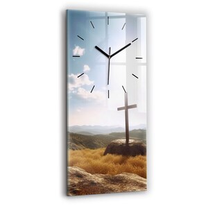 May include: A rectangular wall clock with a landscape scene featuring a cross on a rock in a field of tall grass. The clock face has black hands and hour markers against a sky background.
