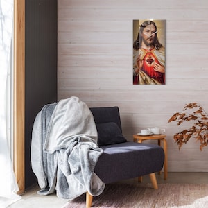 Puede incluir: Una impresión enmarcada de una imagen religiosa que representa a Jesucristo con un corazón en el pecho. La imagen está en un marco dorado y está colgada en una pared de madera blanca.