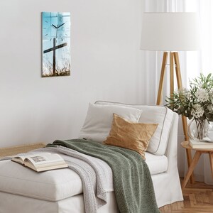 May include: A white couch with a green throw blanket and a brown pillow. A white lamp with a wooden stand is in the background.