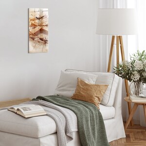 Puede incluir: Un sofá blanco con una manta de lana verde y un cojín beige. Una lámpara blanca con un pie de madera está en el fondo.