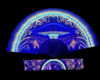 May include: A white folding fan with a blue and purple psychedelic design of a mushroom with a starry sky background. The fan is closed and has a black handle. The fan is made of paper and has a glow-in-the-dark design.