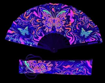 May include: A black folding fan with a neon pink, blue, and orange swirl pattern and a large butterfly design. The fan is closed and has a matching carrying case.