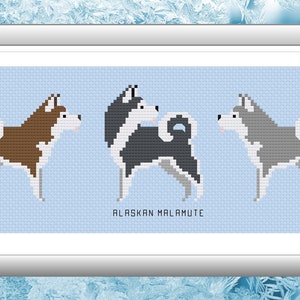May include: Cross-stitch pattern of three Alaskan Malamute dogs in brown, black and white, and gray. The dogs are standing on a light blue background. The text "ALASKAN MALAMUTE" is below the dogs.