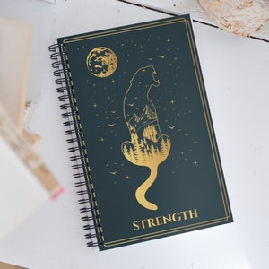 Diário de cartas de tarô de força com um caderno de tarô estético de bruxa dourado e azul