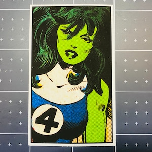 Pu&ograve; includere: Un personaggio di fumetti verde e blu con il numero quattro sul petto. Ha la pelle verde e lunghi capelli verdi.